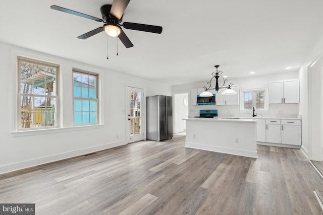 kitchen featuring hanging light fixtures, baseboards, stainless steel appliances, and light wood finished floors