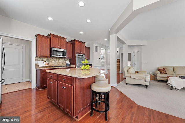 42694 Chisholm, Broadlands, VA 20148 - kitchen featuring stainless steel appliances, open floor plan, a breakfast bar area, backsplash, and wood finished floors