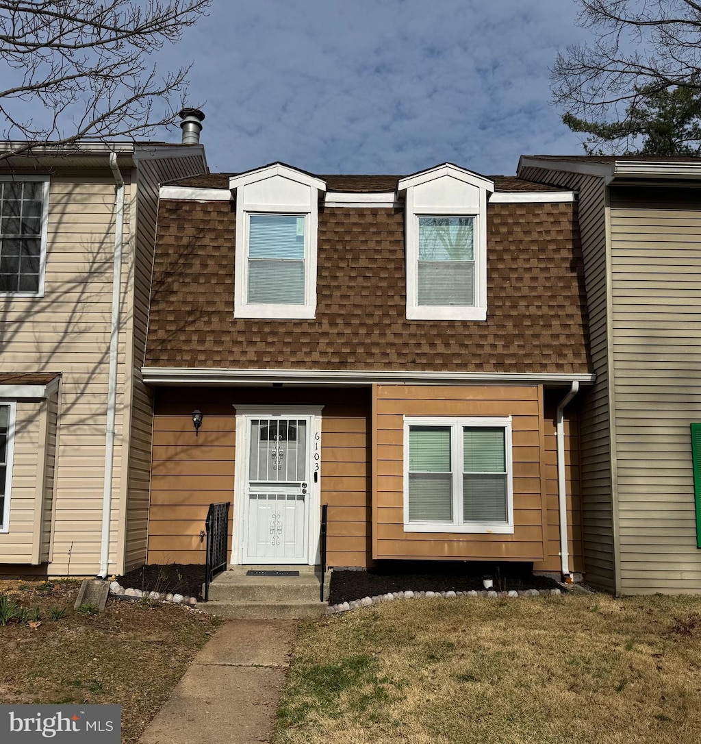 view of front of property with a shingled roof, a front lawn, and mansard roof
