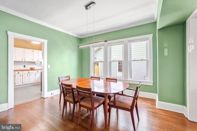 dining room with ornamental molding, baseboards, and hardwood / wood-style floors