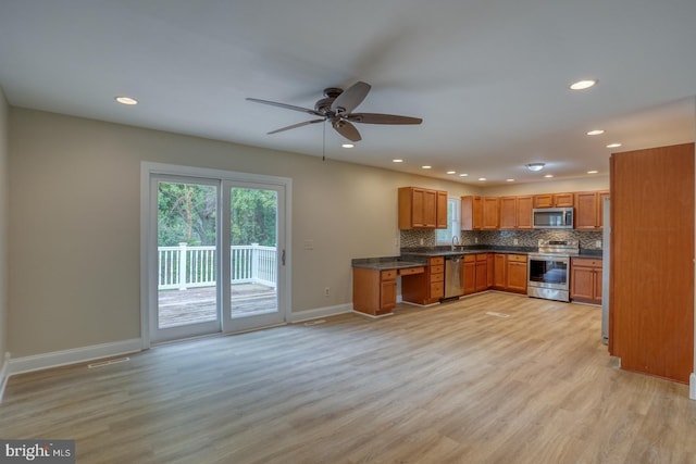 kitchen featuring appliances with stainless steel finishes, dark countertops, tasteful backsplash, light wood-style floors, and recessed lighting