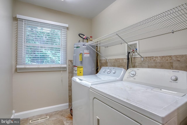 washroom featuring electric water heater, washing machine and clothes dryer, and baseboards