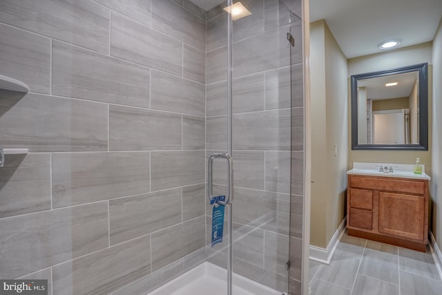 bathroom with a stall shower, baseboards, vanity, and tile patterned flooring