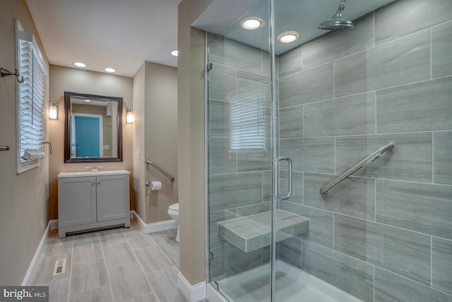 bathroom featuring baseboards, a stall shower, vanity, recessed lighting, and toilet