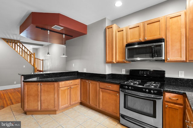 kitchen with dark stone countertops, a peninsula, light tile patterned floors, visible vents, and appliances with stainless steel finishes