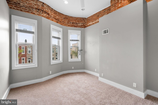 carpeted spare room with a wealth of natural light, visible vents, and baseboards