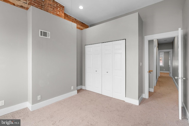 unfurnished bedroom with visible vents, light carpet, baseboards, and a closet
