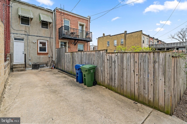 view of home's exterior featuring brick siding, entry steps, a patio, and a fenced backyard