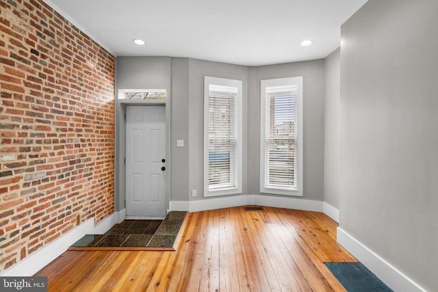 entrance foyer featuring brick wall, recessed lighting, hardwood / wood-style flooring, and baseboards