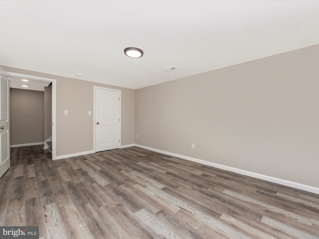 spare room with baseboards, visible vents, and wood finished floors