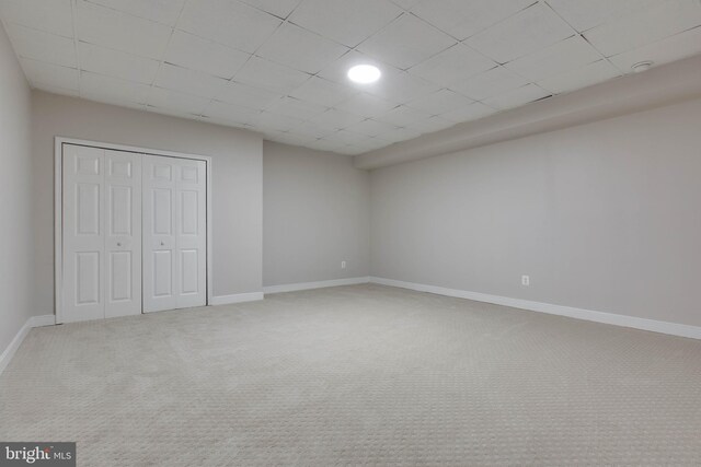 unfurnished bedroom with a closet, baseboards, carpet flooring, and a paneled ceiling