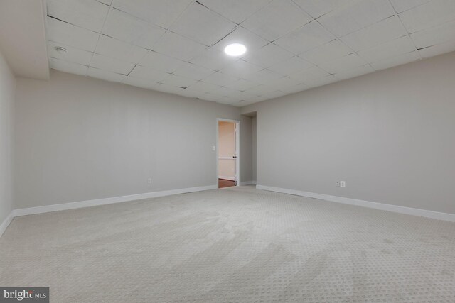 spare room featuring baseboards, carpet, and a paneled ceiling
