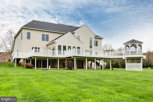 rear view of house featuring a lawn, a gazebo, a wooden deck, and stairs
