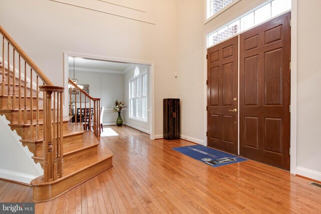 foyer with stairway, baseboards, hardwood / wood-style flooring, and a towering ceiling