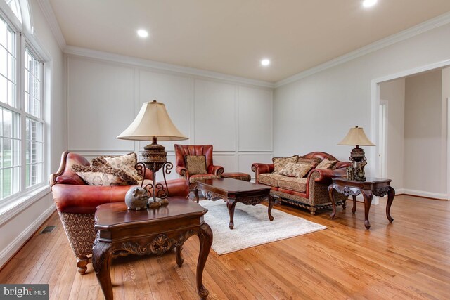 living area with crown molding, plenty of natural light, and light wood finished floors