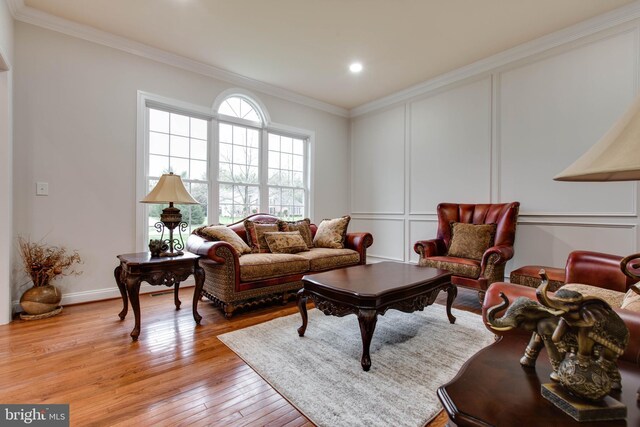 living area with a decorative wall, light wood-style flooring, recessed lighting, baseboards, and ornamental molding