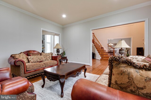 living area with ornamental molding, stairs, and wood finished floors