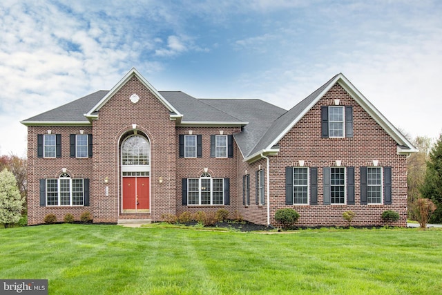 view of front facade featuring brick siding, a shingled roof, and a front lawn