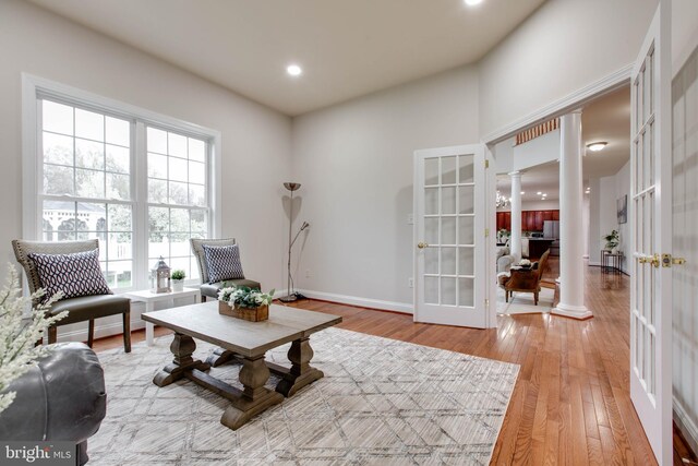 living area with decorative columns, french doors, baseboards, light wood finished floors, and recessed lighting