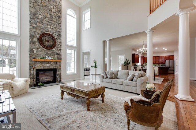 living room featuring ornate columns, light wood finished floors, and a high ceiling