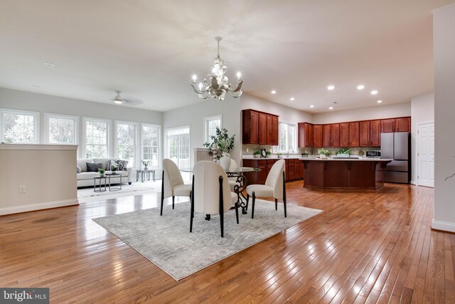 dining room featuring light wood-style floors, baseboards, ceiling fan with notable chandelier, and recessed lighting