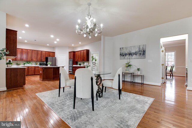 dining area with recessed lighting, baseboards, a notable chandelier, and light wood finished floors