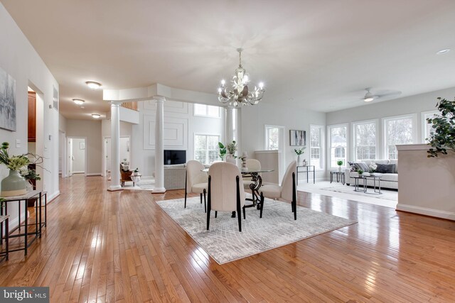 dining space featuring plenty of natural light, light wood finished floors, a fireplace, and decorative columns