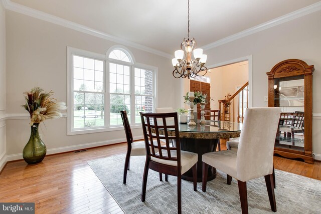 dining space with crown molding, an inviting chandelier, a wealth of natural light, and light wood-style flooring