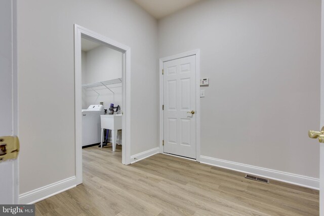 laundry area featuring laundry area, visible vents, baseboards, washer / dryer, and light wood-style flooring