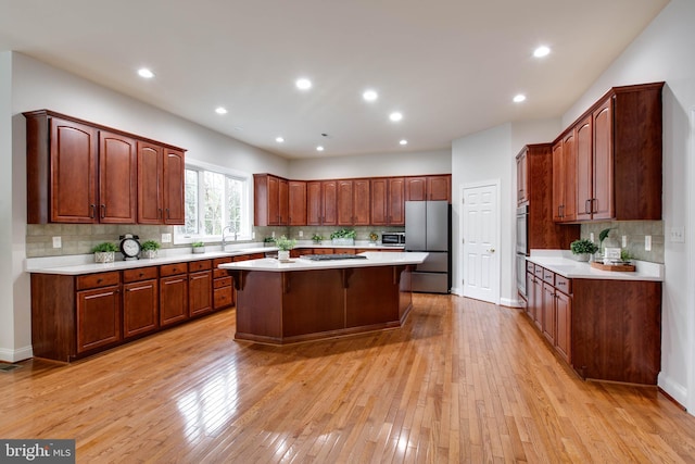 kitchen with light countertops, a kitchen island, backsplash, and stainless steel appliances