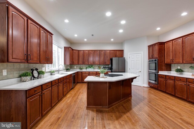 kitchen featuring a sink, appliances with stainless steel finishes, decorative backsplash, and light wood-style flooring