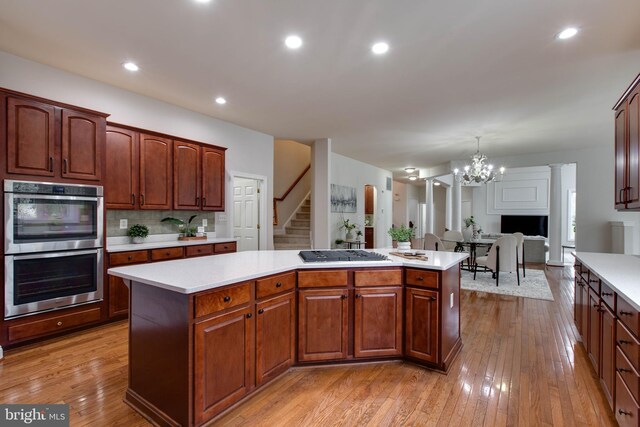 kitchen featuring appliances with stainless steel finishes, a center island, light countertops, a notable chandelier, and light wood-style flooring
