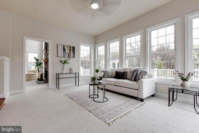 carpeted living area featuring baseboards and a ceiling fan