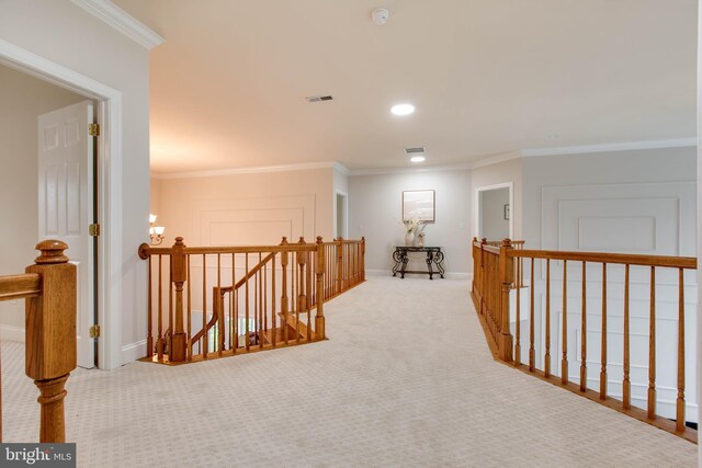 corridor featuring visible vents, crown molding, baseboards, an upstairs landing, and carpet flooring