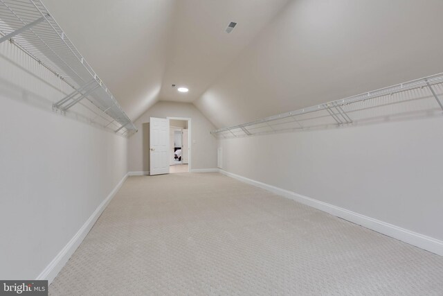 walk in closet with carpet and lofted ceiling
