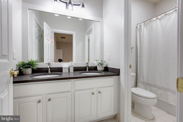 bathroom featuring double vanity, a sink, tile patterned floors, and toilet