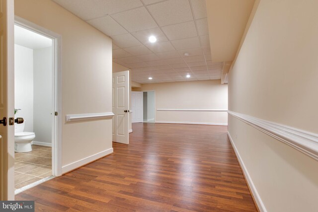 hall with baseboards, a drop ceiling, recessed lighting, and wood finished floors