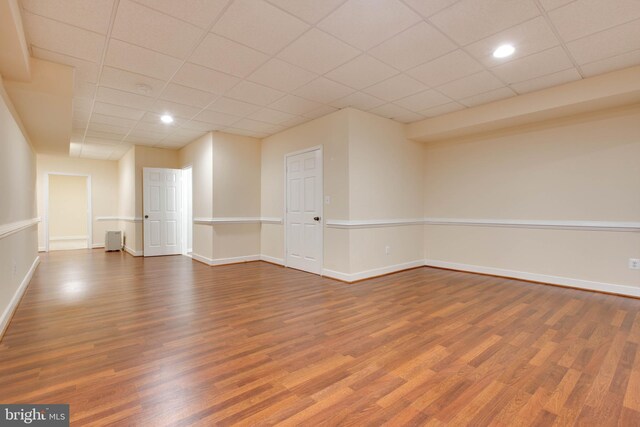 spare room with recessed lighting, baseboards, a drop ceiling, and wood finished floors