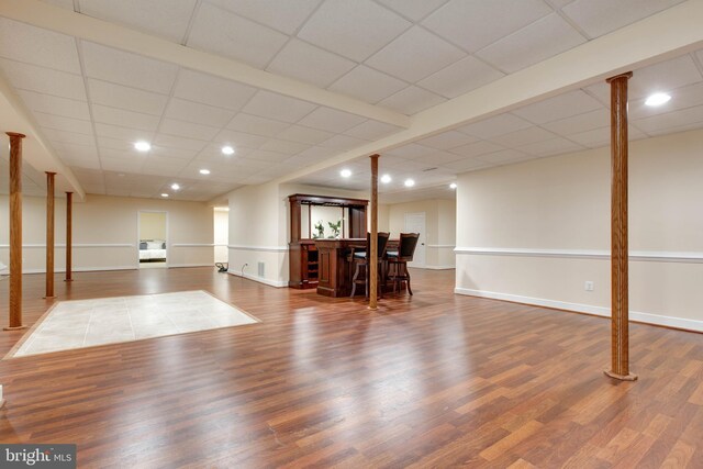 interior space featuring baseboards, a paneled ceiling, and wood finished floors