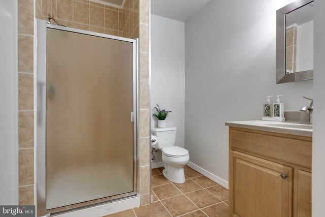 bathroom with tile patterned flooring, a stall shower, vanity, baseboards, and toilet
