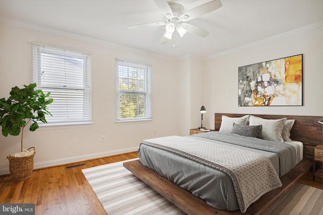 bedroom featuring ornamental molding, baseboards, wood finished floors, and a ceiling fan