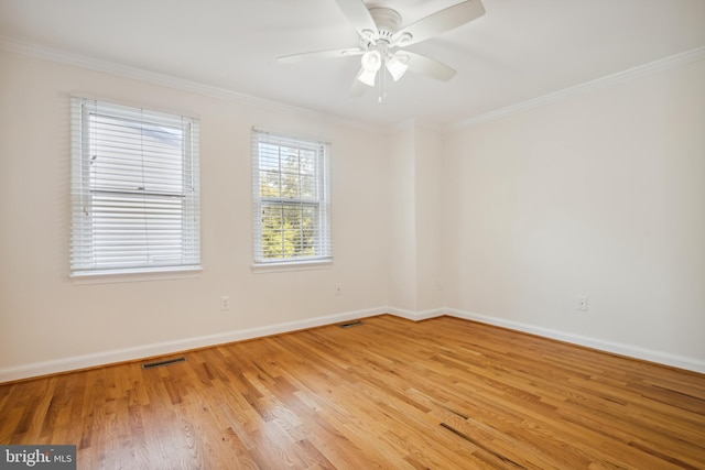 empty room with ornamental molding, light wood-style flooring, baseboards, and a ceiling fan