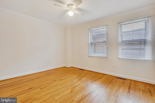 empty room featuring wood finished floors, ornamental molding, baseboards, and a ceiling fan
