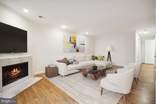 living area with ornamental molding, a fireplace, recessed lighting, hardwood / wood-style flooring, and baseboards