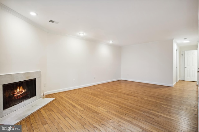 unfurnished living room featuring ornamental molding, a fireplace, baseboards, recessed lighting, and light wood finished floors