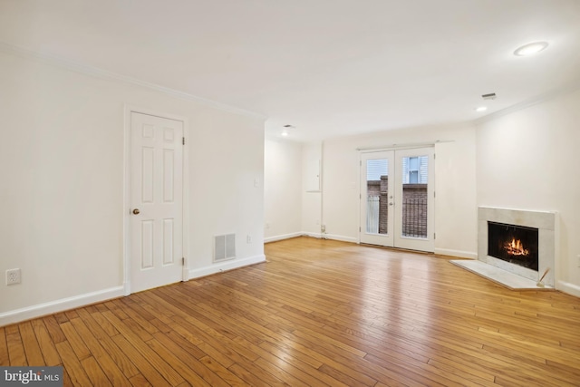 unfurnished living room featuring light wood-type flooring, a high end fireplace, crown molding, baseboards, and recessed lighting