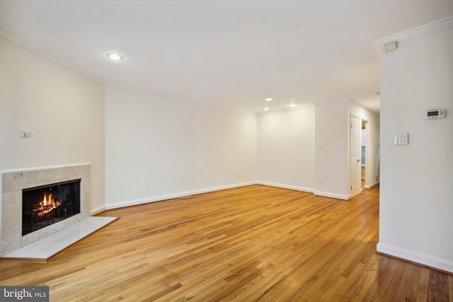 unfurnished living room featuring a fireplace, light wood-style flooring, ornamental molding, baseboards, and recessed lighting