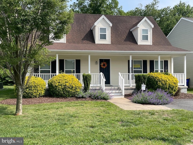 view of front of property featuring a shingled roof, a front lawn, and a porch