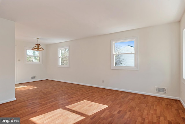 empty room featuring baseboards, visible vents, and light wood-type flooring