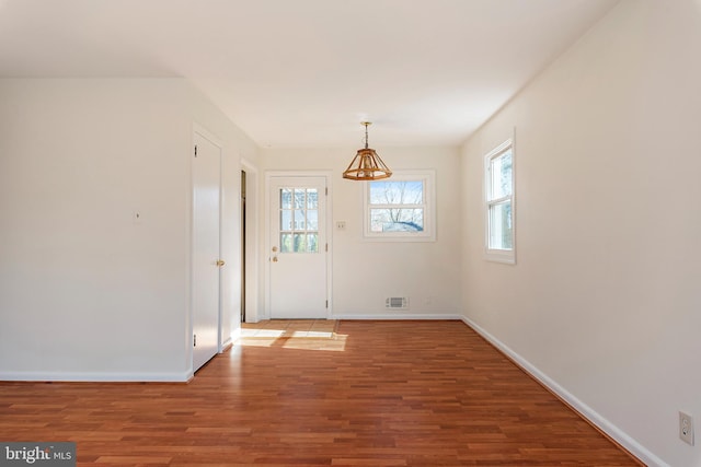 foyer with wood finished floors, baseboards, and visible vents